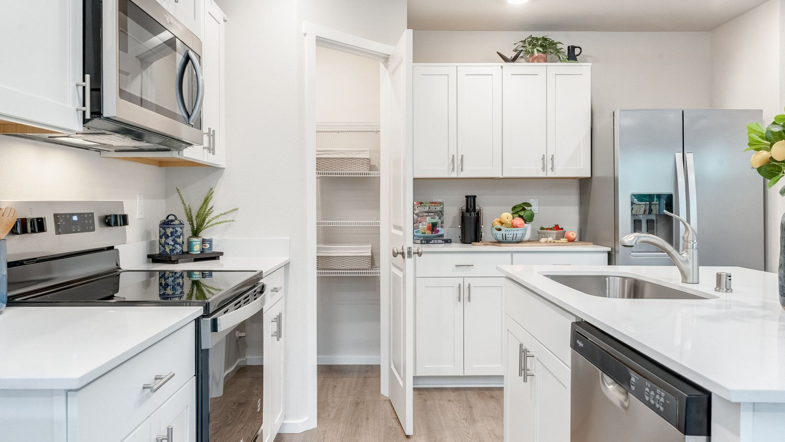 Kitchen with shaker cabinets, quartz counters, stainless steel appliances, pantry, and an island with a breakfast bar