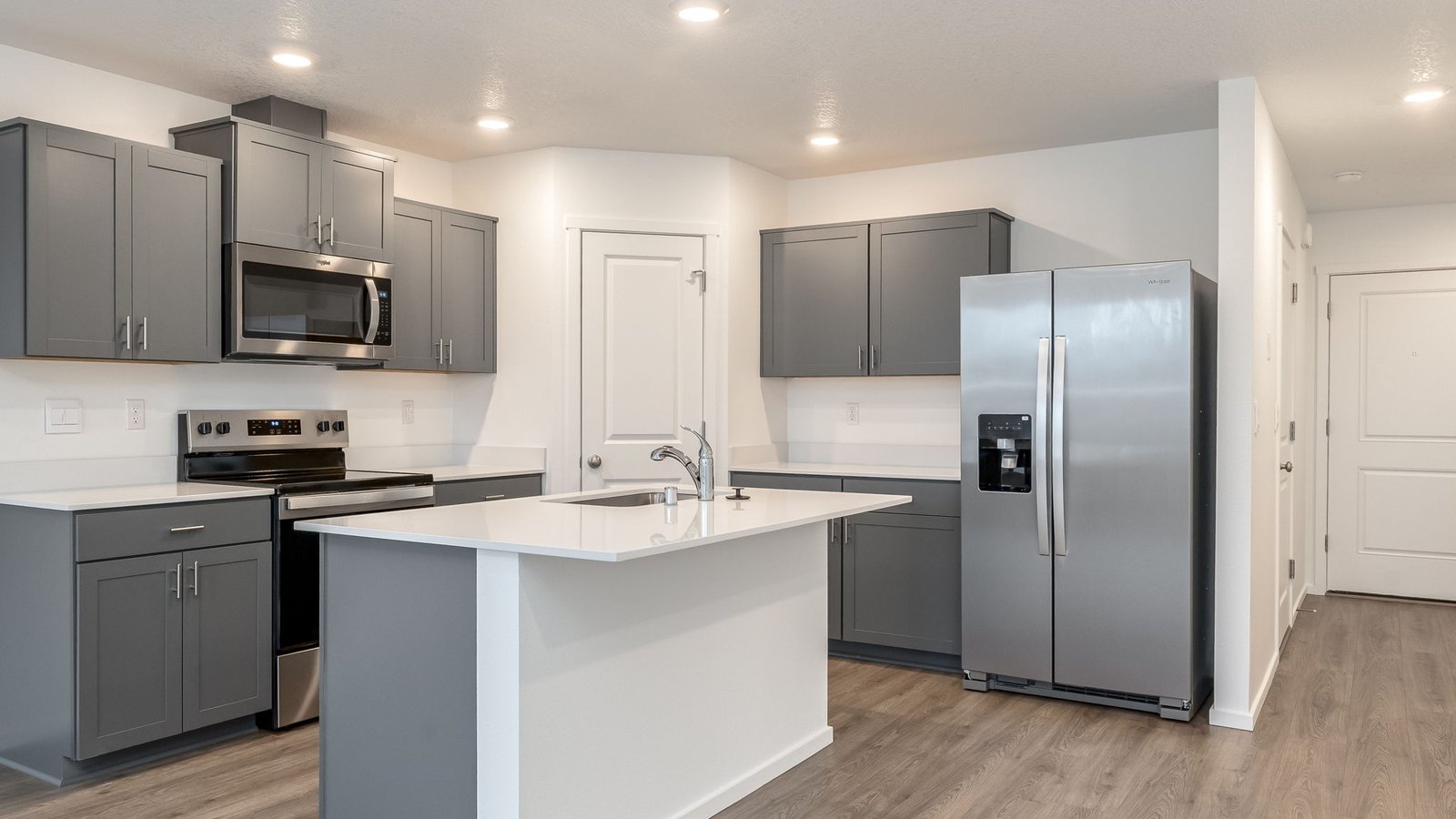 Kitchen with shaker cabinets, quartz counters, stainless steel appliances, pantry, and an island with a breakfast bar