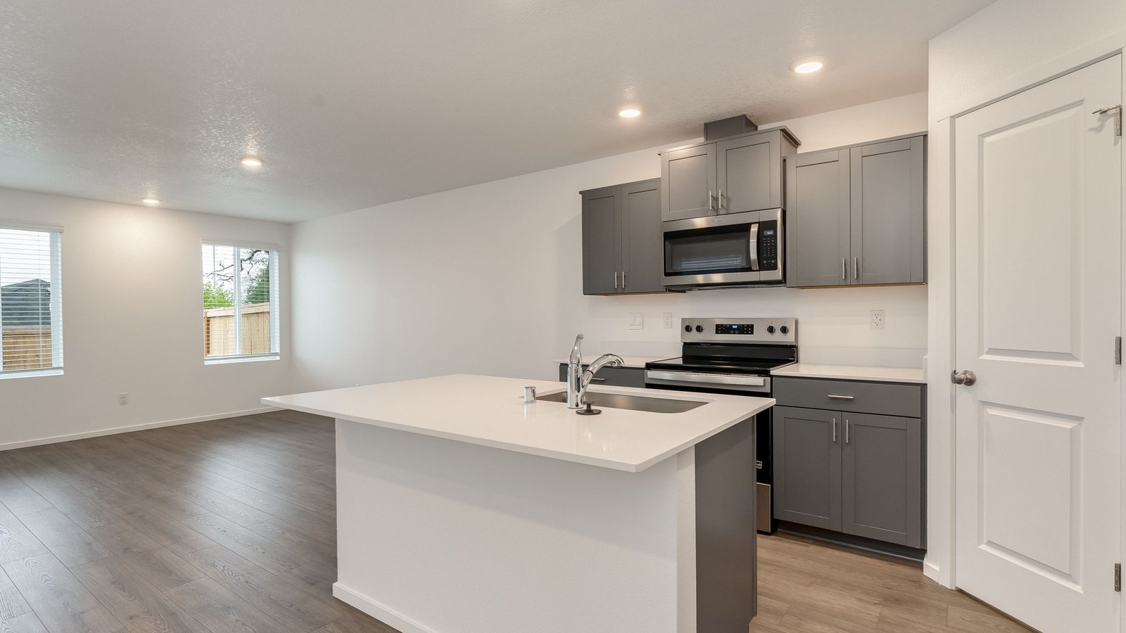 Kitchen with shaker cabinets, quartz counters, stainless steel appliances, pantry, and an island with a breakfast bar