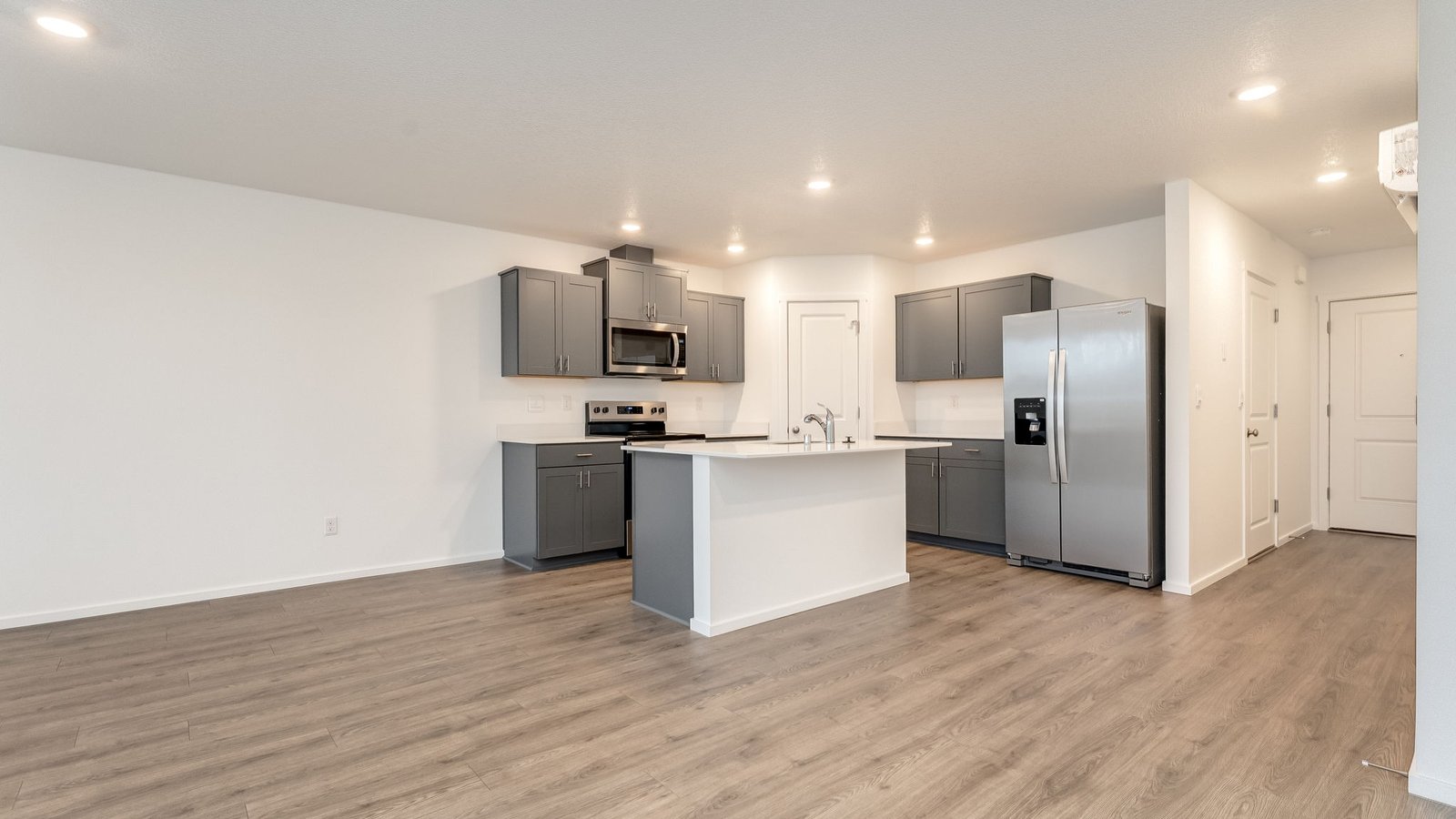 Kitchen with shaker cabinets, quartz counters, stainless steel appliances, pantry, and an island with a breakfast bar