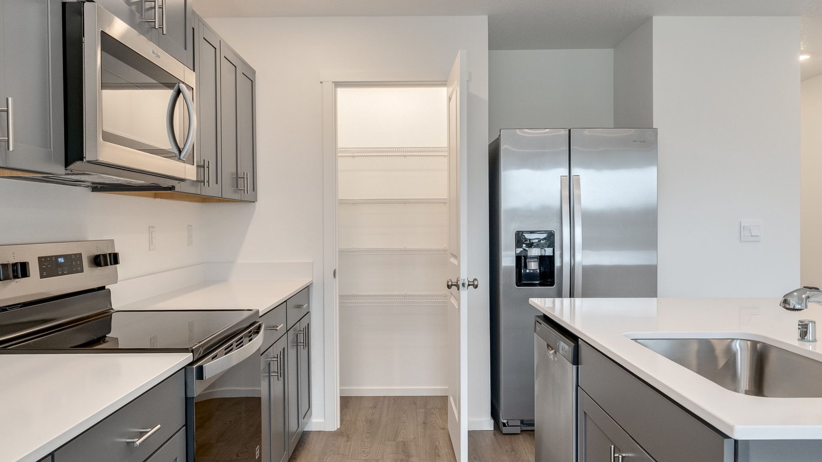 Kitchen with shaker cabinets, quartz counters, stainless steel appliances, pantry, and an island with a breakfast bar