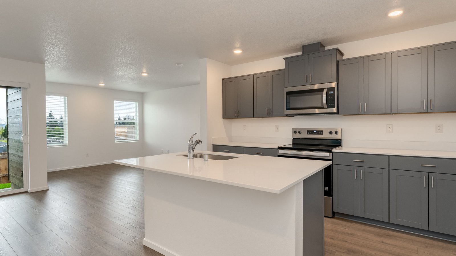 Kitchen with shaker cabinets, quartz counters, stainless steel appliances, pantry, and an island with a breakfast bar