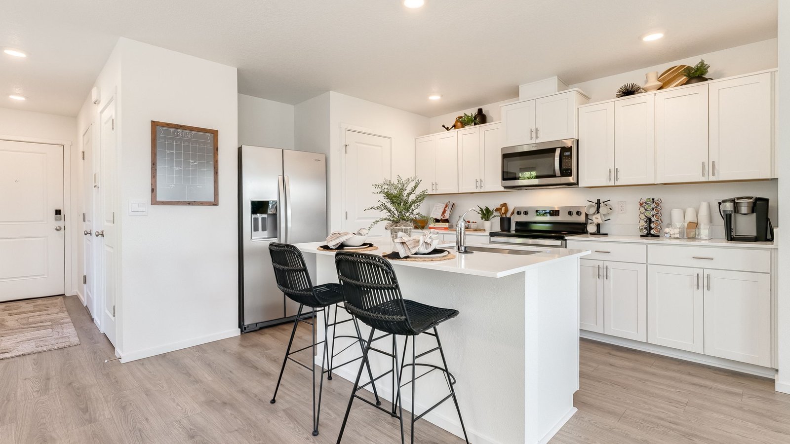 Kitchen with shaker cabinets, quartz counters, stainless steel appliances, pantry, and an island with a breakfast bar