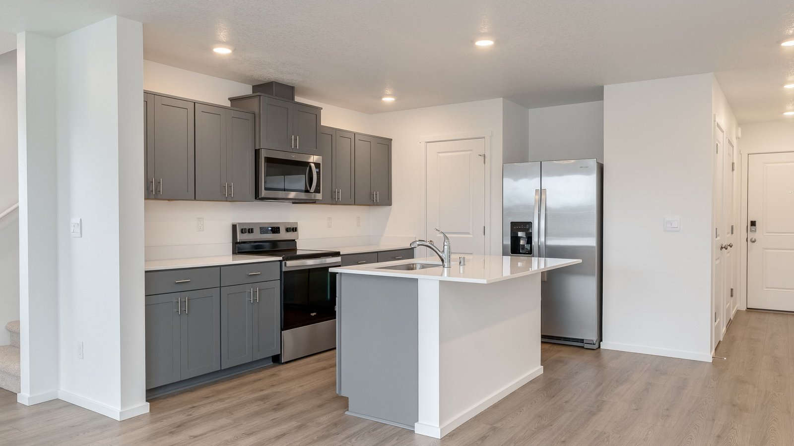 Kitchen with shaker cabinets, quartz counters, stainless steel appliances, pantry, and an island with a breakfast bar