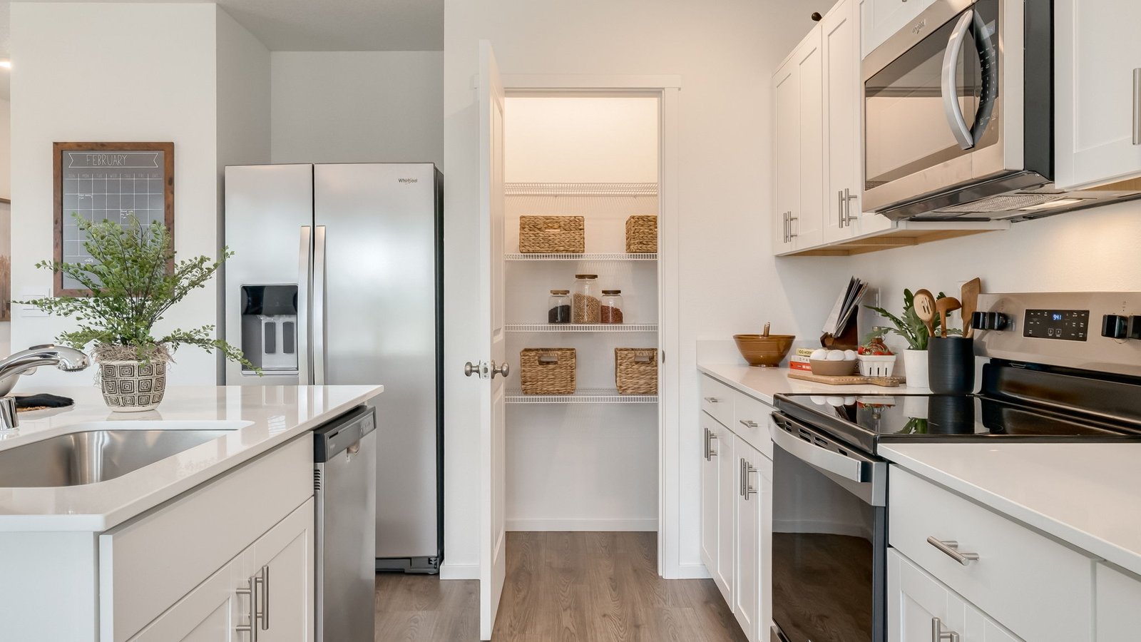 Kitchen with shaker cabinets, quartz counters, stainless steel appliances, pantry, and an island with a breakfast bar