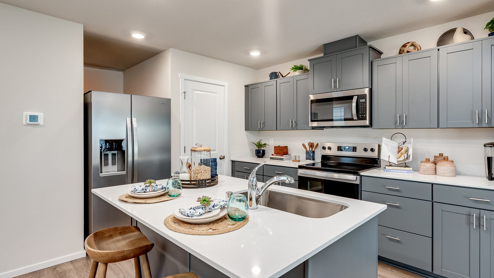 Kitchen with shaker cabinets, quartz counters, stainless steel appliances, pantry, and an island with a breakfast bar