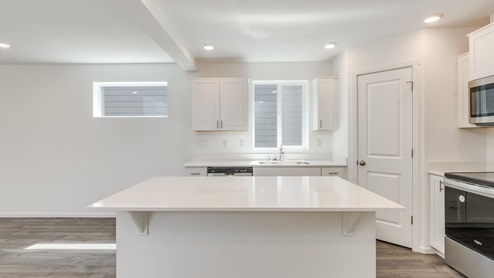 Kitchen with shaker cabinets, quartz counters, stainless steel appliances, pantry, and an island with a breakfast bar