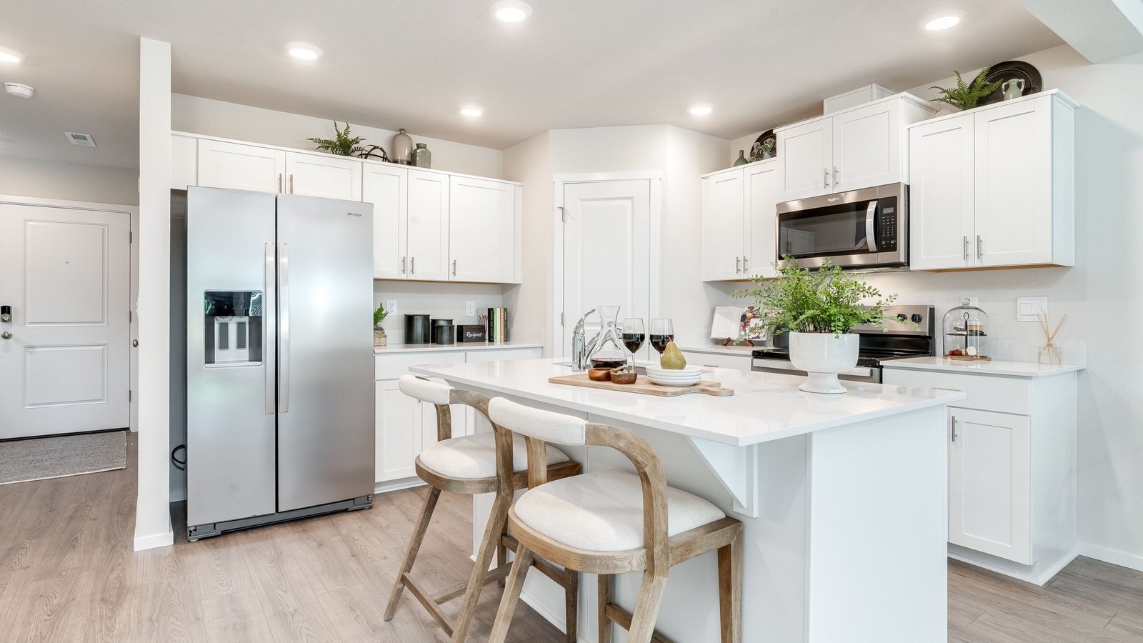 Kitchen with shaker cabinets, quartz counters, stainless steel appliances, pantry, and an island with a breakfast bar