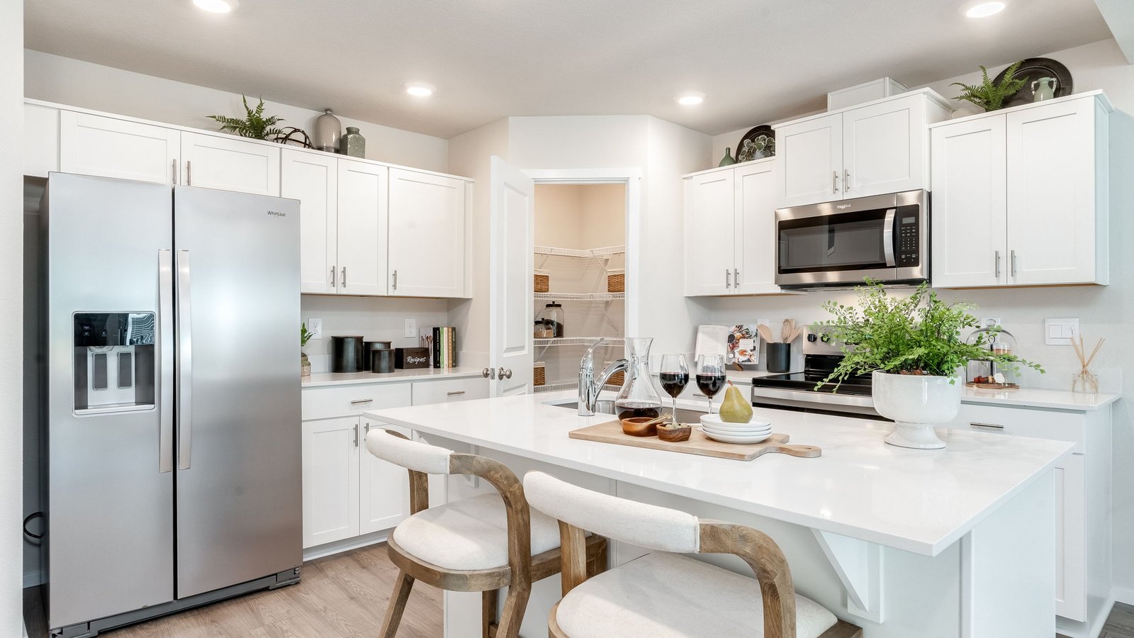 Kitchen with shaker cabinets, quartz counters, stainless steel appliances, pantry, and an island with a breakfast bar