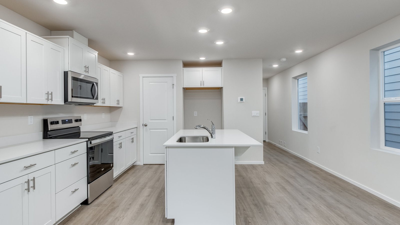 Kitchen with shaker cabinets, quartz counters, stainless steel appliances, pantry, and an island with a breakfast bar