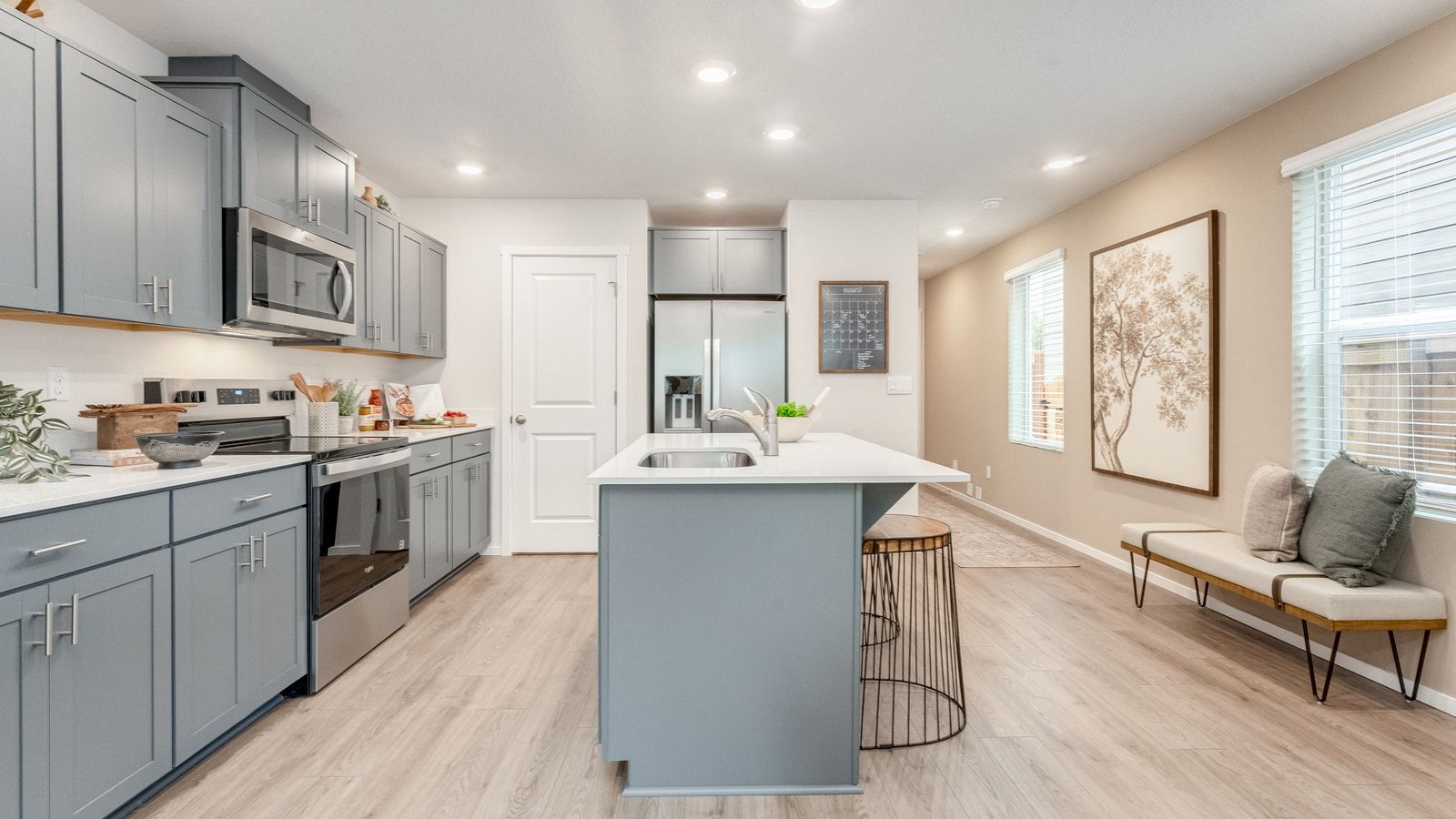 Kitchen with shaker cabinets, quartz counters, stainless steel appliances, pantry, and an island with a breakfast bar
