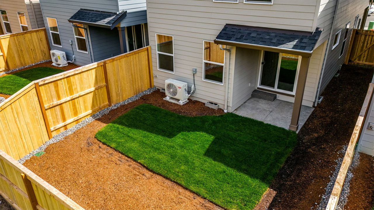 fully fenced backyard with sod lawn and a patio
