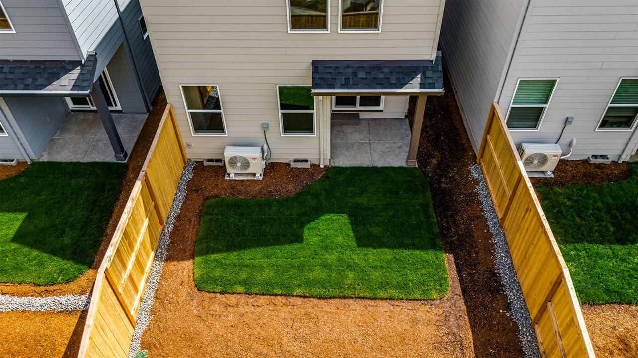 fully fenced backyard with sod lawn and a patio
