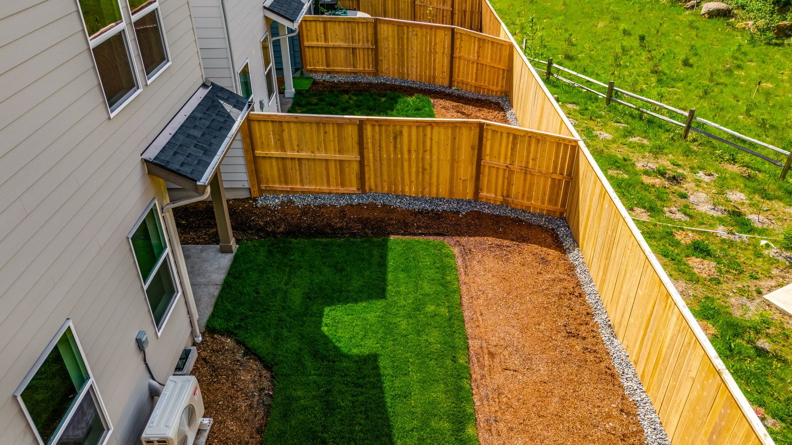 fully fenced backyard with sod lawn and a patio