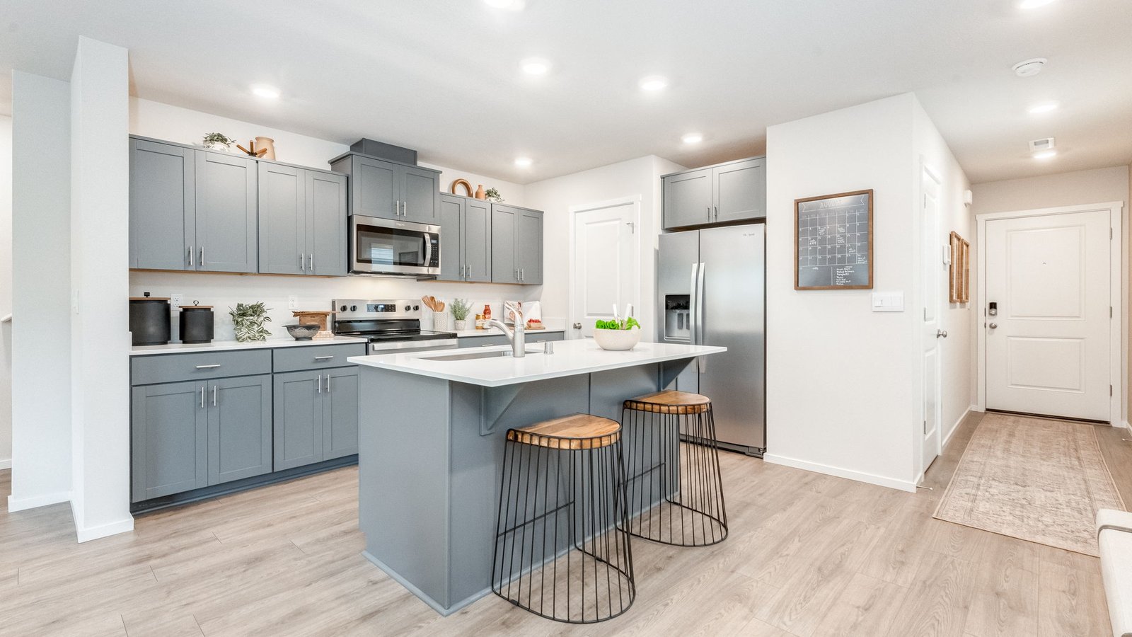 Kitchen with shaker cabinets, quartz counters, stainless steel appliances, pantry, and an island with a breakfast bar