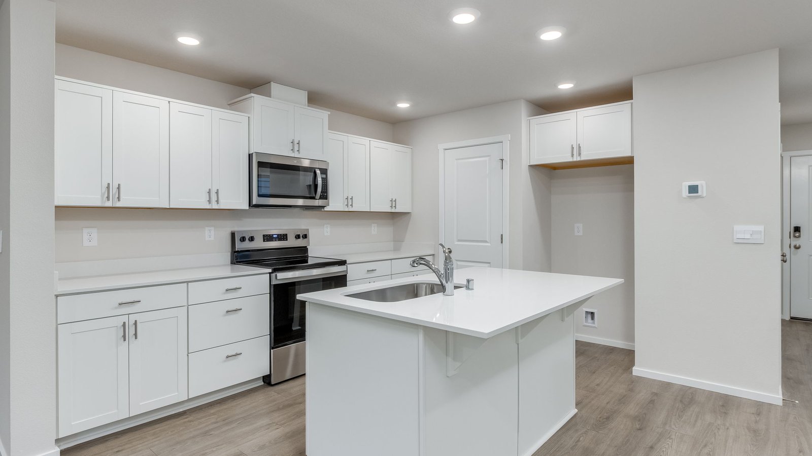 Kitchen with shaker cabinets, quartz counters, stainless steel appliances, pantry, and an island with a breakfast bar