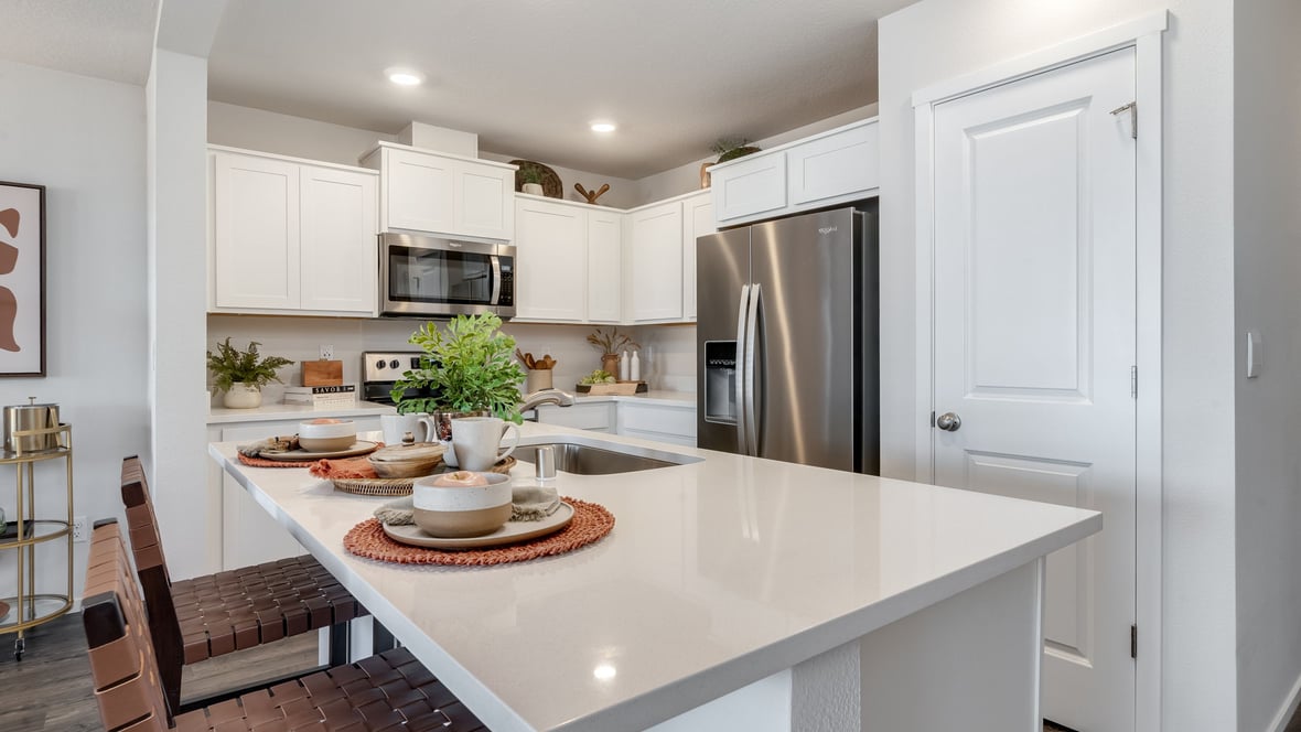 Kitchen with shaker cabinets, quartz counters, stainless steel appliances, pantry, and an island with a breakfast bar