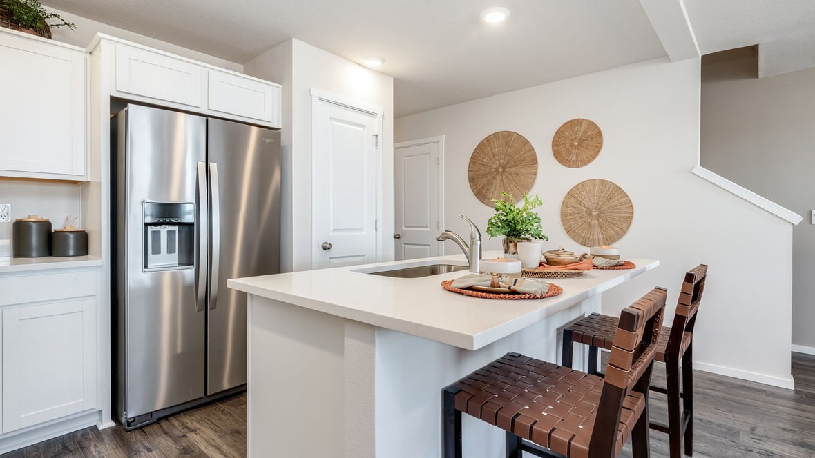 Kitchen with shaker cabinets, quartz counters, stainless steel appliances, pantry, and an island with a breakfast bar