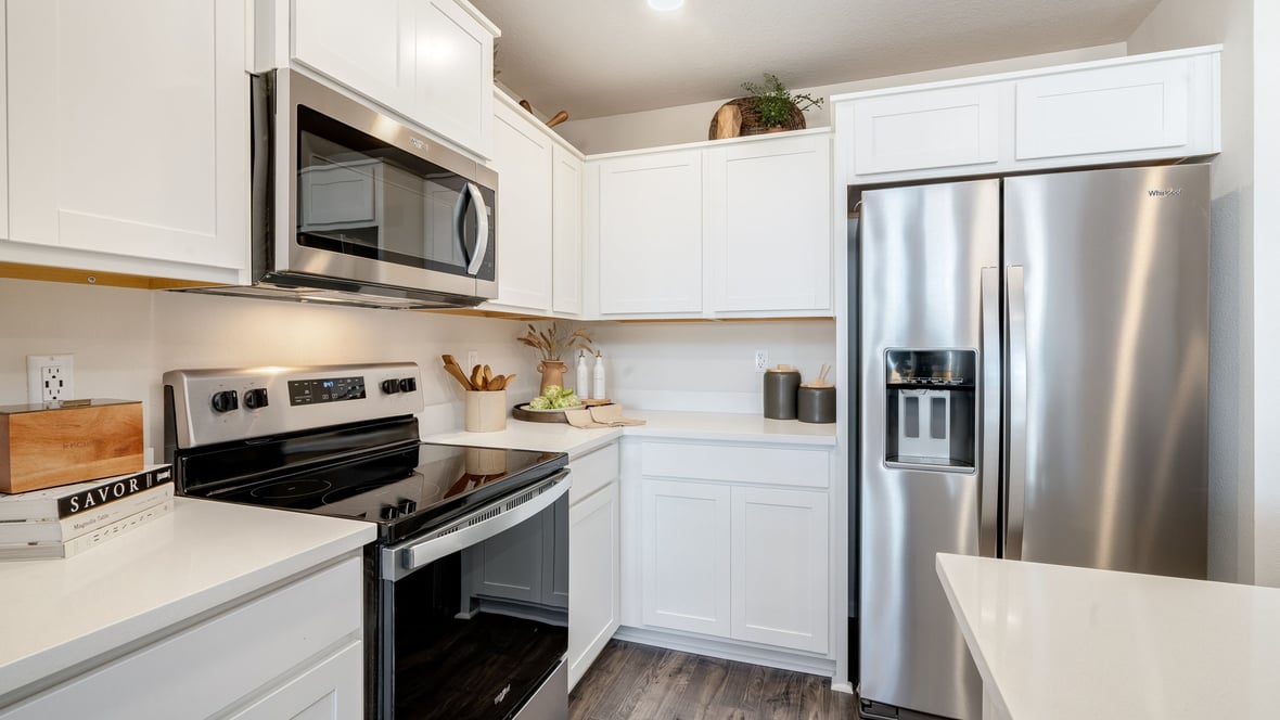 Kitchen with shaker cabinets, quartz counters, stainless steel appliances, pantry, and an island with a breakfast bar