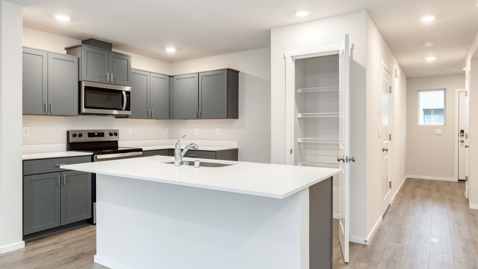 Kitchen with shaker cabinets, quartz counters, stainless steel appliances, pantry, and an island with a breakfast bar