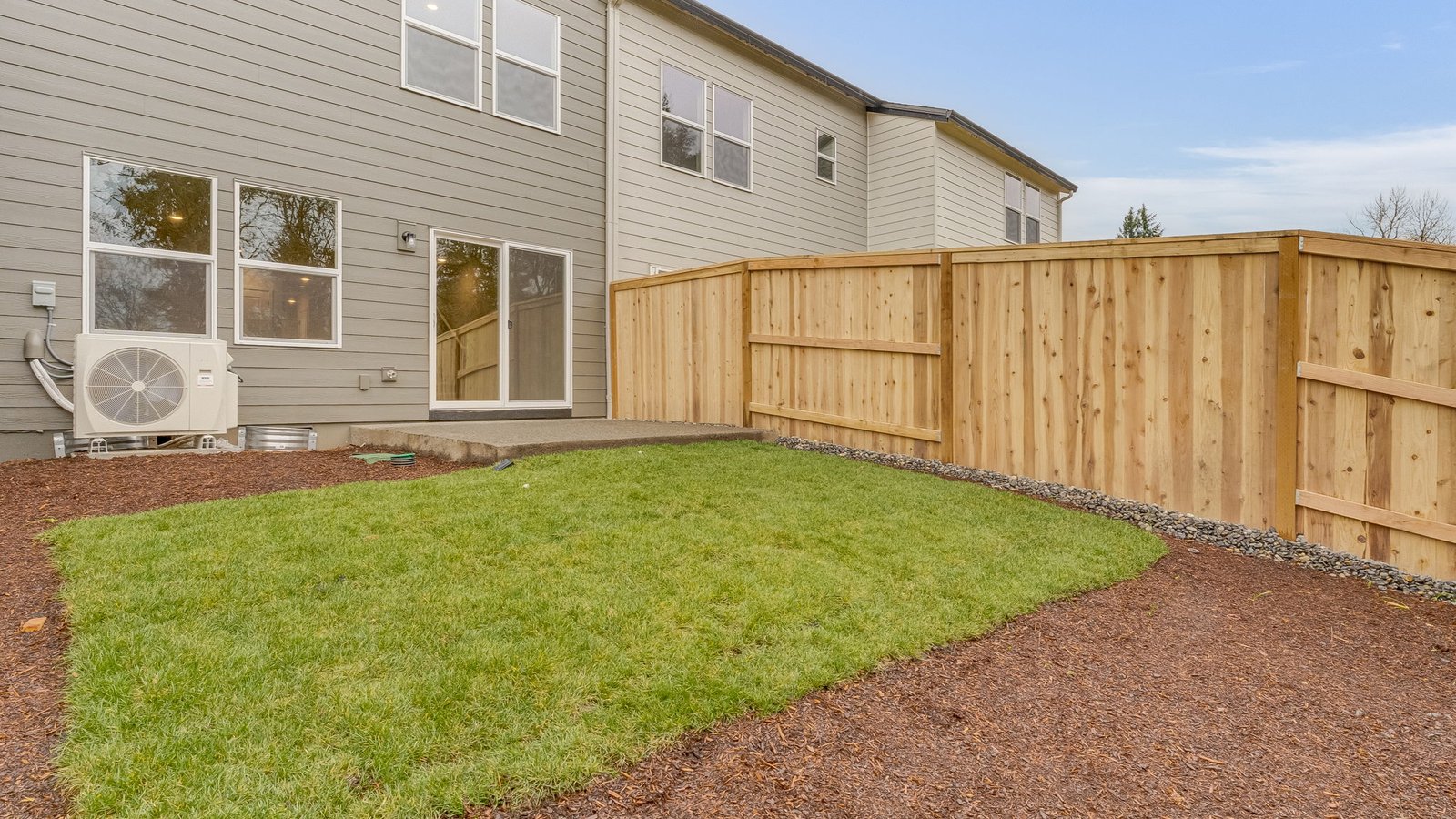 fully fenced backyard with sod lawn and a patio