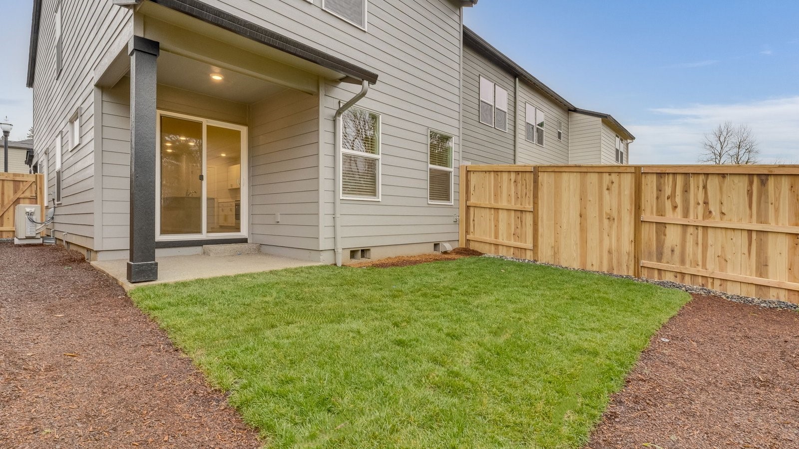 fully fenced backyard with sod lawn and a patio