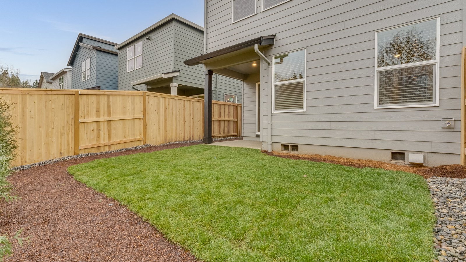 fully fenced backyard with sod lawn and a patio