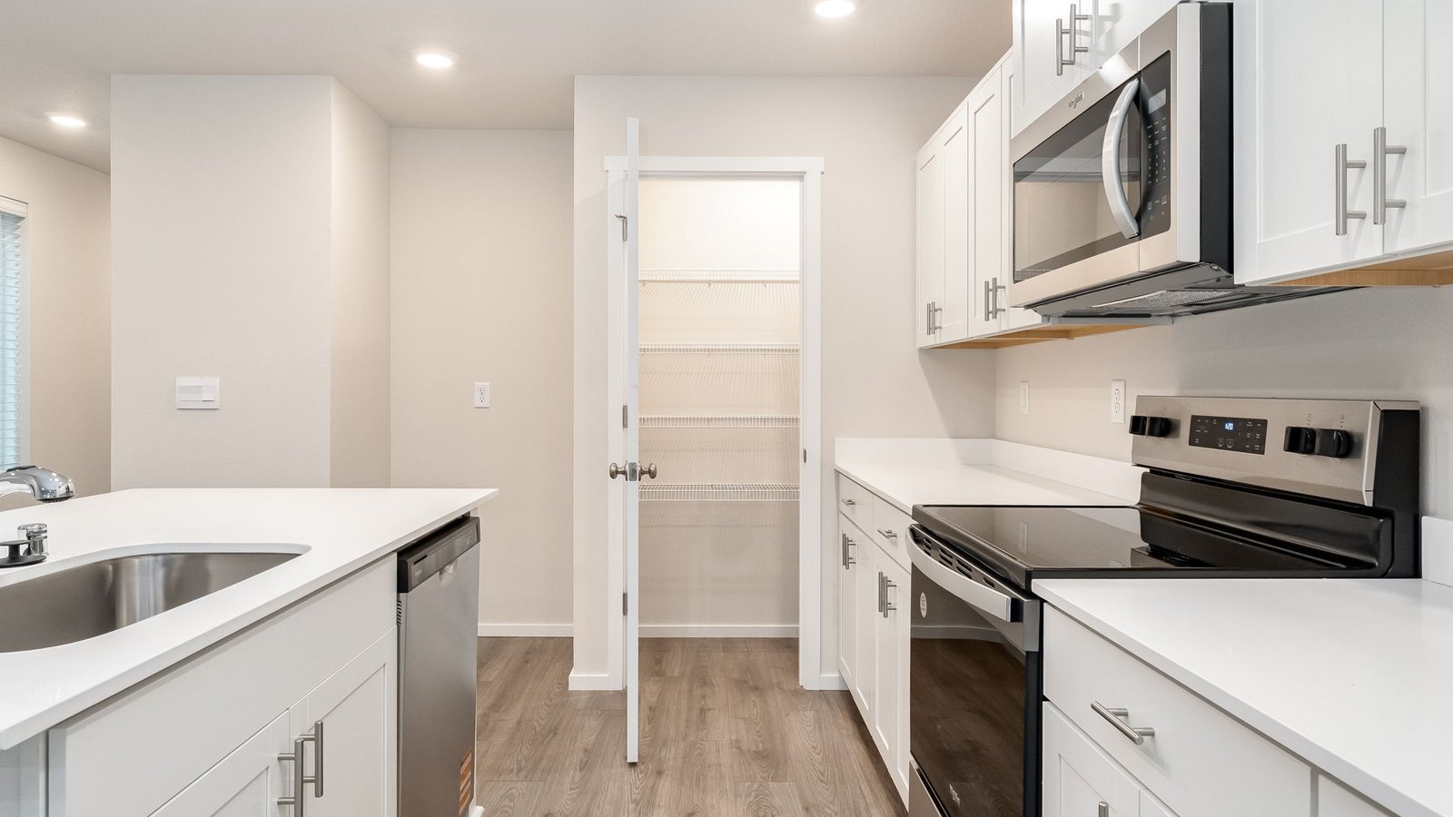 Kitchen with shaker cabinets, quartz counters, stainless steel appliances, pantry, and an island with a breakfast bar