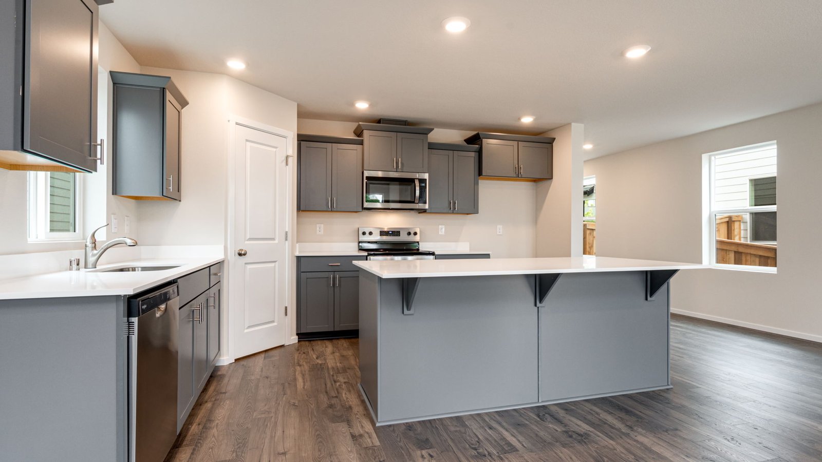 Kitchen with shaker cabinets, quartz counters, stainless steel appliances, pantry, and an island with a breakfast bar