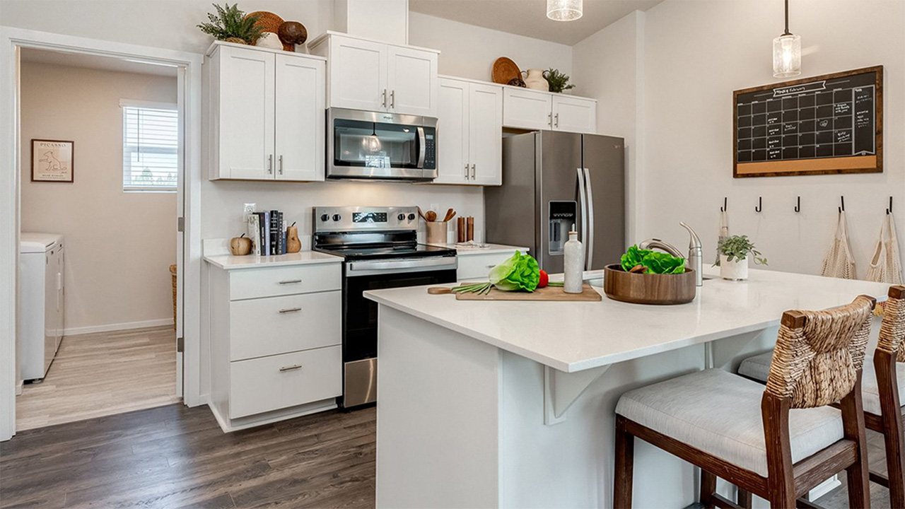 Kitchen with shaker cabinets, quartz counters, stainless steel appliances, pantry, and an island with a breakfast bar