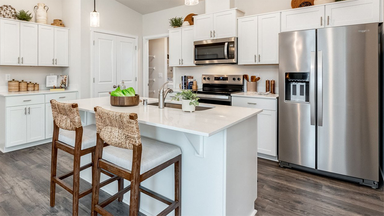 Kitchen with shaker cabinets, quartz counters, stainless steel appliances, pantry, and an island with a breakfast bar