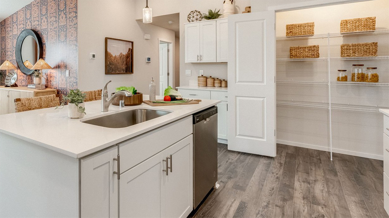 Kitchen with shaker cabinets, quartz counters, stainless steel appliances, pantry, and an island with a breakfast bar