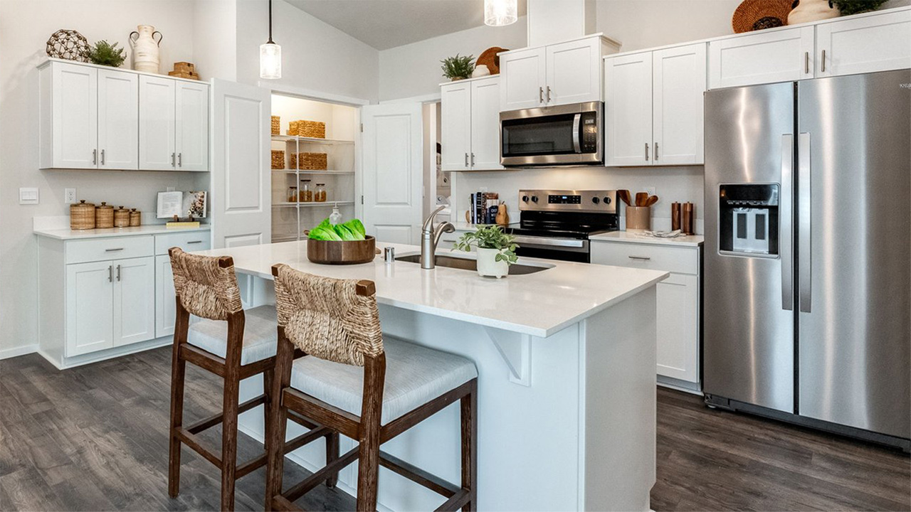 Kitchen with shaker cabinets, quartz counters, stainless steel appliances, pantry, and an island with a breakfast bar