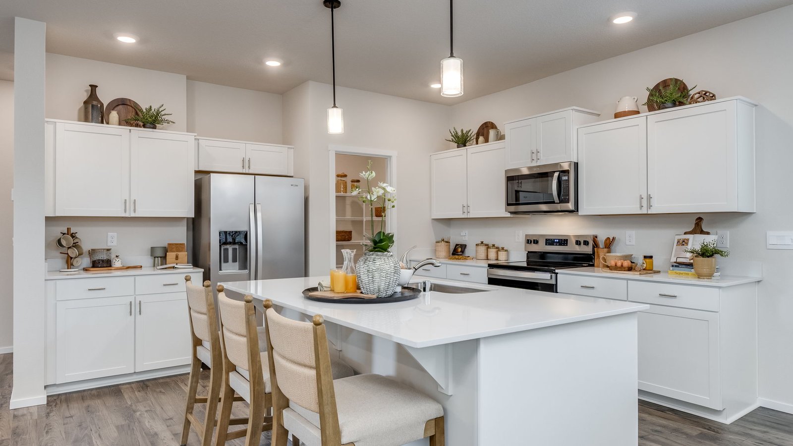 Kitchen with shaker cabinets, quartz counters, stainless steel appliances, pantry, and an island with a breakfast bar