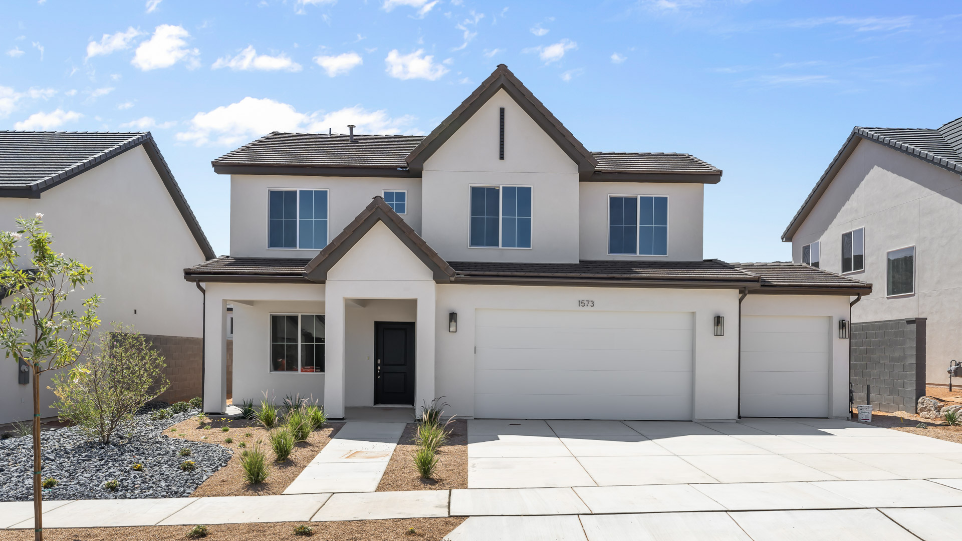 brand new Scandinavian style home with white stucco and black trim with a three car garage