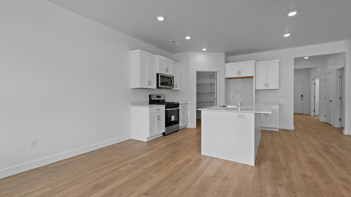 Spacious kitchen with a large quartz island, stainless steel appliances, and corner pantry