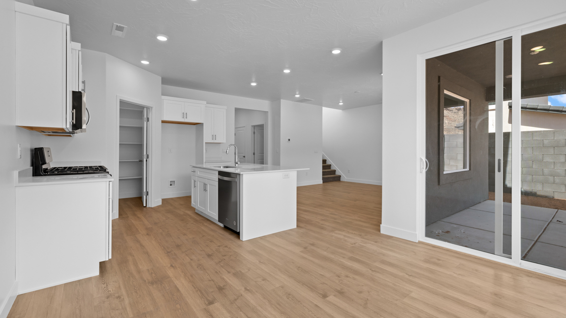 Spacious kitchen with a large quartz island, stainless steel appliances, and corner pantry