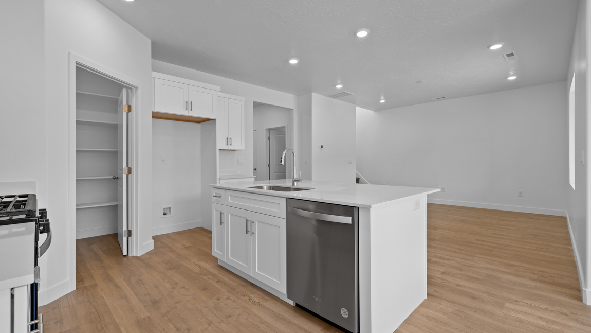 Spacious kitchen with a large quartz island, stainless steel appliances, and corner pantry