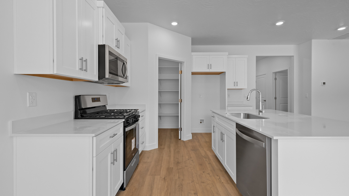 Spacious kitchen with a large quartz island, stainless steel appliances, and corner pantry