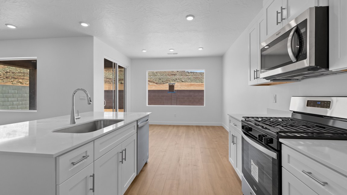 Spacious kitchen with a large quartz island, stainless steel appliances, and corner pantry