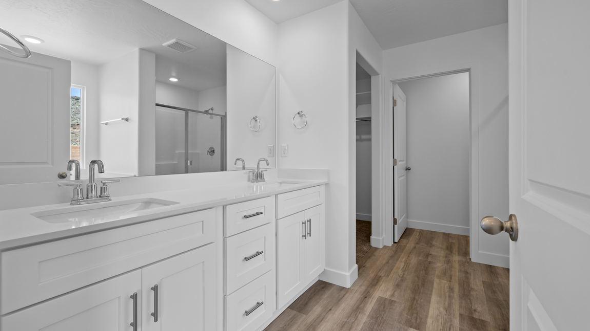 Large primary bathroom with quartz countertops, double sink vanity, and separate walk in shower and garden tub with window