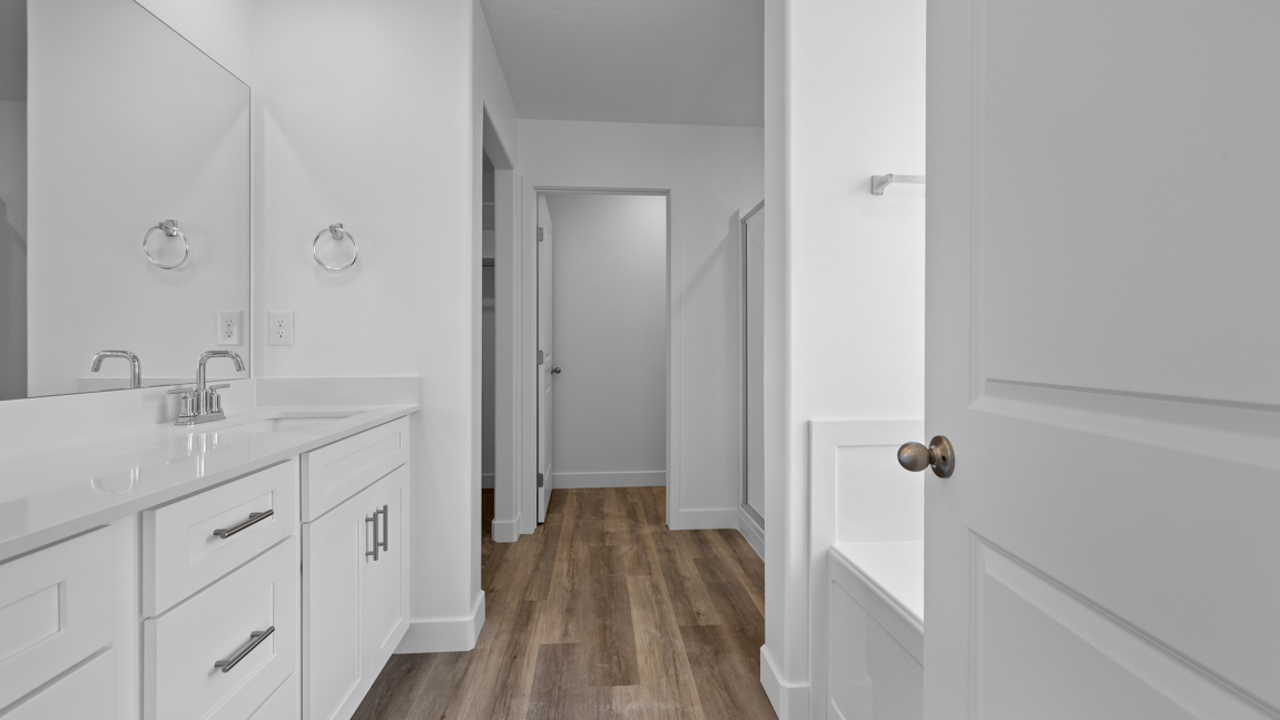 Large primary bathroom with quartz countertops, double sink vanity, and separate walk in shower and garden tub with window