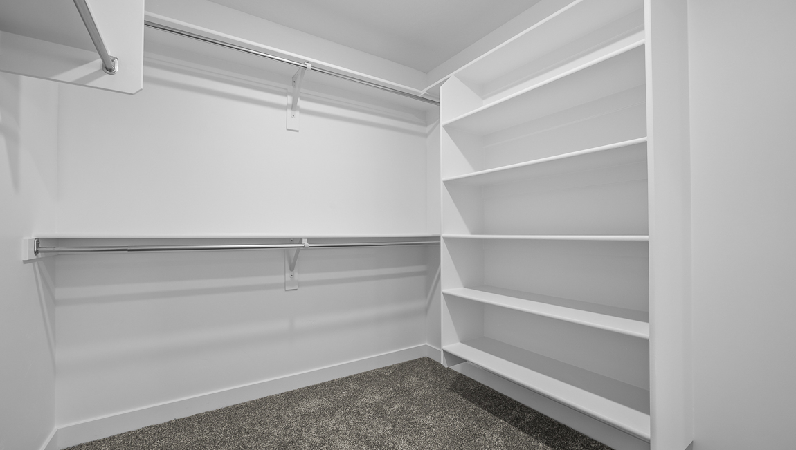 Primary walk in closet with built in shelving