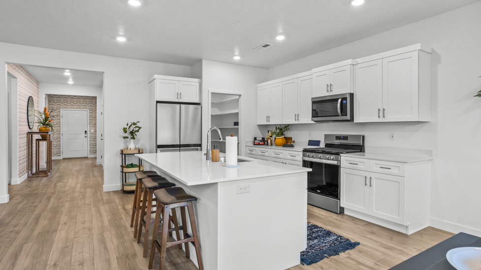 Spacious kitchen with a large quartz island, stainless steel appliances, and corner pantry