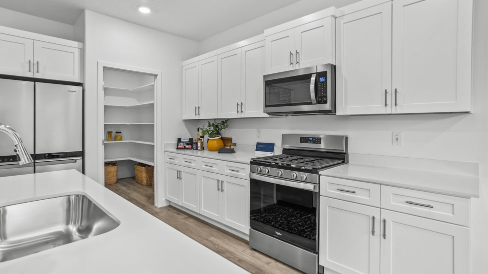 Spacious kitchen with a large quartz island, stainless steel appliances, and corner pantry