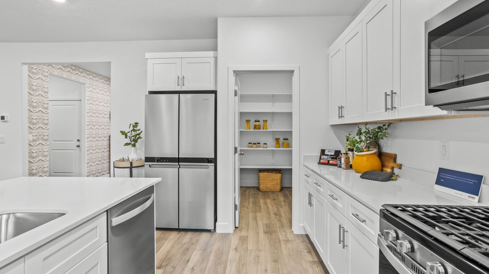 Spacious kitchen with a large quartz island, stainless steel appliances, and corner pantry