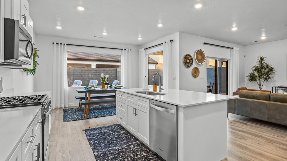 Spacious kitchen with a large quartz island, stainless steel appliances, and corner pantry