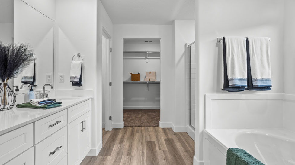Large primary bathroom with quartz countertops, double sink vanity, and separate walk in shower and garden tub with window