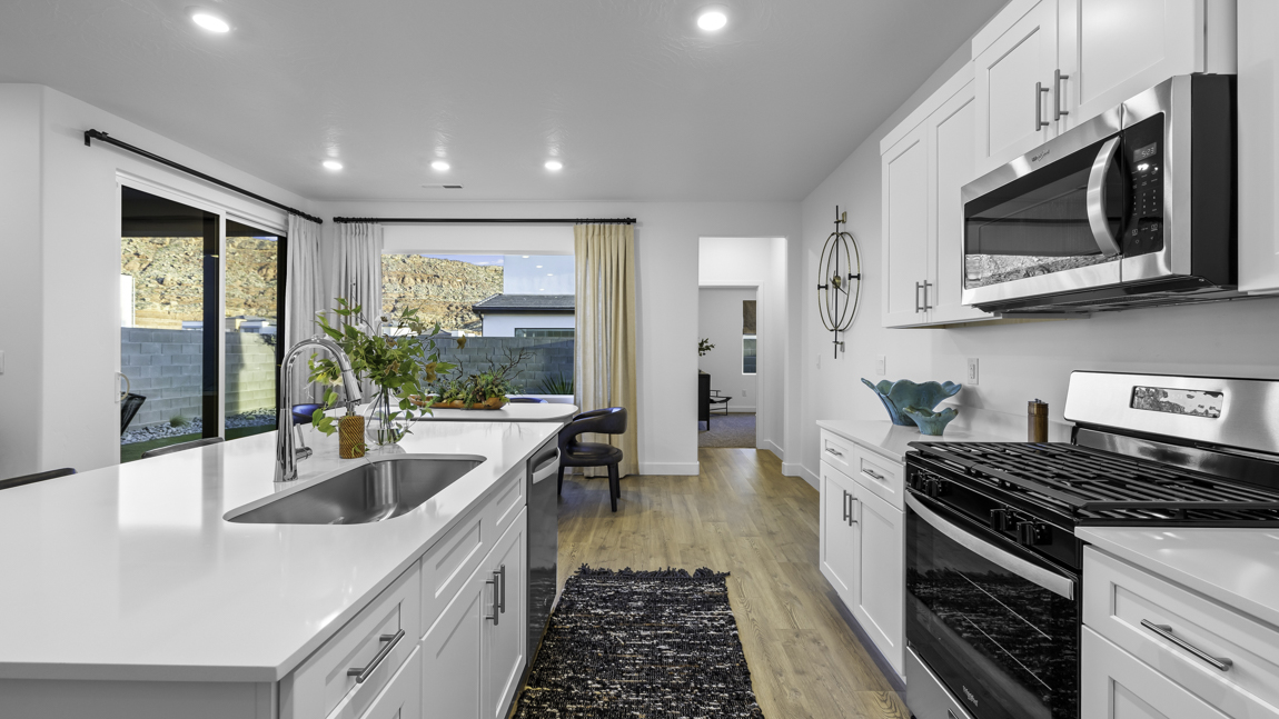 Spacious kitchen with a large quartz island, stainless steel appliances, and corner pantry