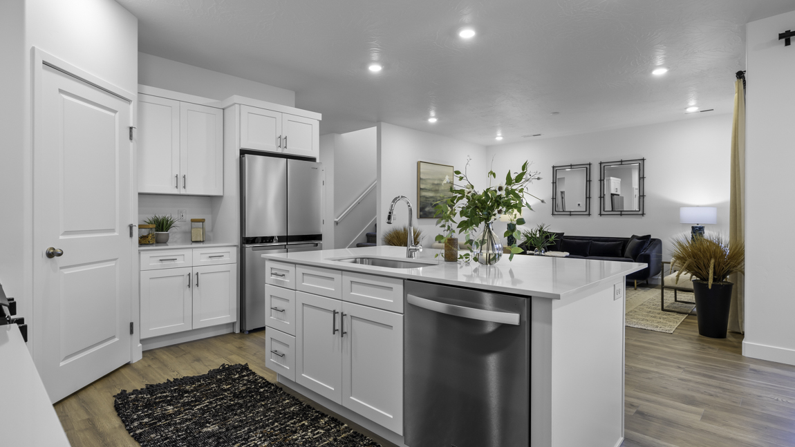 Spacious kitchen with a large quartz island, stainless steel appliances, and corner pantry